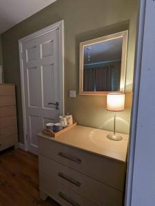 a bedroom with a dresser with a lamp and a mirror at TeachinTom in Strabane
