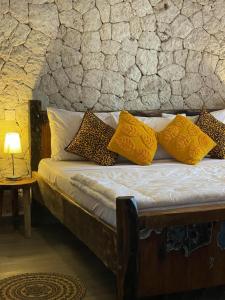 Villa tangawizi kendwa في كيندوا: سرير مع وسائد صفراء وجدار حجري
