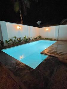 a large blue swimming pool at night with a wooden deck at Villa tangawizi kendwa in Kendwa