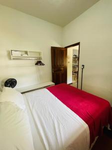 1 dormitorio con 1 cama grande con manta roja en Casinha 87 en Tiradentes