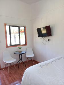 a bedroom with a bed and a table and two chairs at Alojamiento Ximena in Coñaripe