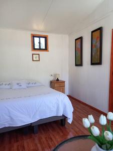 a bedroom with a bed and a window and a table at Alojamiento Ximena in Coñaripe