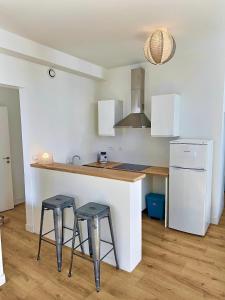 een keuken met 2 krukken en een aanrecht met een koelkast bij WonderHost, au cœur du quartier du château in Pau