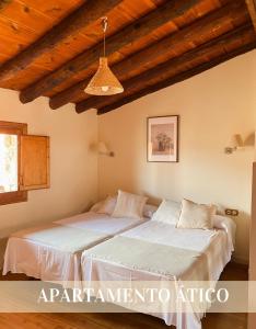 two beds in a room with wooden ceilings at Alojamientos Apolonia, La Fresneda in La Fresneda