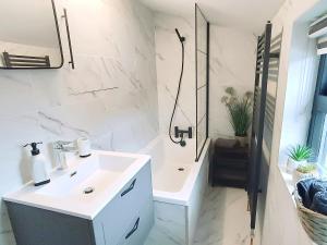 biała łazienka z umywalką i prysznicem w obiekcie Stansted Airport Cottage w mieście Bishop's Stortford