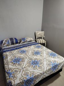 uma cama com um edredão azul e branco e uma cadeira em Hostel Bauti en Ezeiza em Ezeiza