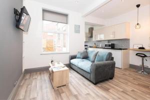 a living room with a blue couch and a kitchen at Modern home near the hopsital in Exeter