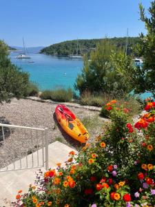 a yellow kayak sitting on the rocks next to flowers at Luxury Villa Kate - in Lucice Bay with turquoise sea, Amazing Seaviews, and Heated Pool in Milna