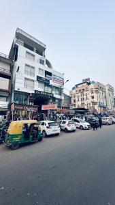 una concurrida calle de la ciudad con coches estacionados frente a los edificios en Hotel Relax In - Noida Sector 18 en Noida