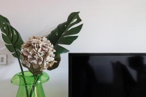 a vase with a flower in it next to a tv at Luxury and elegant apartment Rome Vatican in Rome