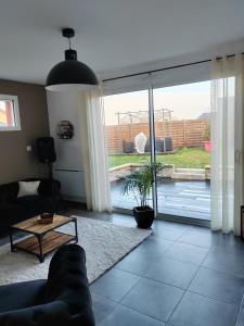 a living room with a couch and a sliding glass door at La maison des noyers in Parigné-lʼÉvêque