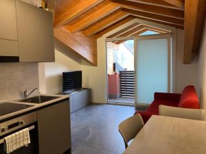 Residence La Corte di San Rocco في Cremeno: مطبخ مع طاولة وأريكة حمراء في غرفة