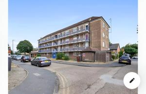 een groot bakstenen gebouw op een straat met auto's geparkeerd bij The Serene Flat W Free Street Parking in Hackbridge