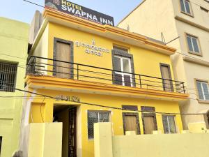 un bâtiment jaune avec un panneau en haut dans l'établissement Hotel Swapna Inn, à Purî