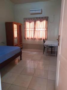 a bedroom with a bed and a table and a window at Kapowlito Real Estate Casa Hendrikstraat in Paramaribo