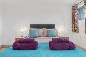 a bedroom with a large bed with purple pillows at Ramsey Sea View Cottage - Dog Friendly in Pembrokeshire