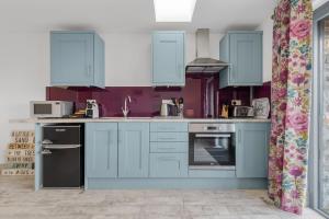 a kitchen with blue cabinets and purple walls at Ramsey Sea View Cottage - Dog Friendly in Pembrokeshire