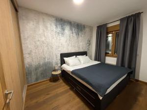 a bedroom with a bed with a gray wall at Tenea Apartment & SPA in Zlatibor