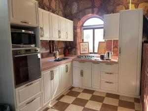 a kitchen with white cabinets and a window at Red Mountain Farm in Al-ʿUla