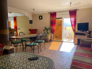 a living room with a table and chairs and a television at The Rainbow House in Mirleft