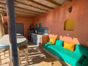 a living room with a green couch and a kitchen at The Rainbow House in Mirleft