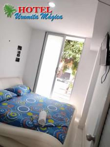a bed in a room with a large window at Hotel URUMITA MAGICA in Valledupar