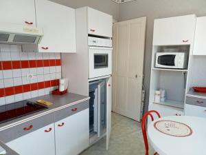 a kitchen with white cabinets and a table and a microwave at F2 1ER ETAGE - 5 min du Lac de Madine in Vigneulles-lès-Hattonchâtel