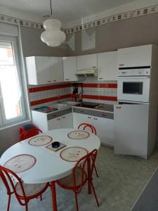 uma cozinha com uma mesa e cadeiras brancas e um frigorífico branco em F2 1ER ETAGE em Vigneulles-lès-Hattonchâtel