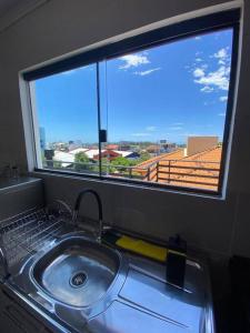 a sink in front of a window with a view at Linda cobertura, vistas para o mar a 300m da praia in Florianópolis