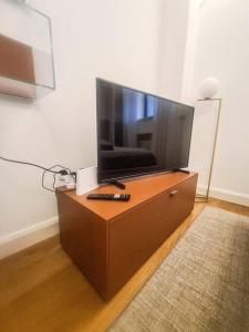 TV de pantalla plana en la parte superior de una cómoda de madera en Porta Nuova Apartment, en Milán