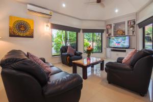 a living room with leather furniture and a tv at Baan Leelawadee - 4 Bed Villa near Beach Pattaya in Nong Prue