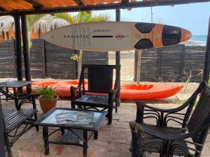mesa y sillas con tabla de surf en la playa en Marinus Eco Lodge, en Canoas