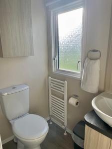 a bathroom with a toilet and a sink and a window at Newquay Bay Resort Sandy Toes - Hosting up to 6 in Newquay