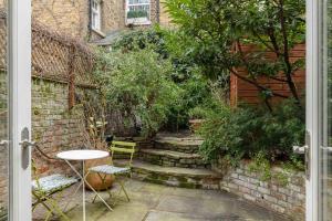 a patio with a table and chairs next to a brick wall at A Grand Four Bedroom Townhouse at Knightsbridge in London