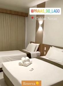 Praias do Lago Eco Resort 1 quarto في كالدس نوفاس: سريرين في غرفة فندق مع مناشف عليهما
