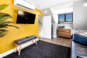 a living room with a couch and a tv on a yellow wall at 30 on Whites Guesthouse in Bloemfontein
