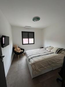 een witte slaapkamer met een bed en een stoel bij Villa 6 personnes avec piscine in Istres