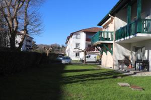 a yard next to a white building with a green balcony at BOKATEA in Cambo-les-Bains