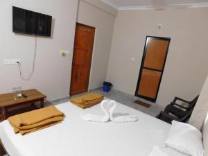 a room with two beds and a table and a television at Ariel Guesthouse in Baga