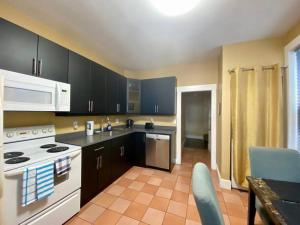 a kitchen with black cabinets and a white stove top oven at Large Townhouse, Lower Floor with AC, City Center in Halifax