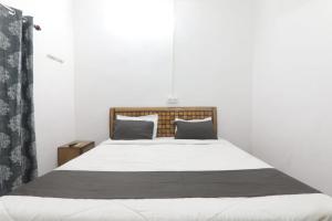 una camera da letto con letto, lenzuola e cuscini bianchi di Chitraa guest house a Prayagraj