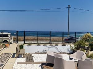 un gruppo di sedie bianche e un tavolo e l'oceano di Maison du golf a Costinesti