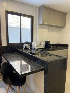 a kitchen with a black counter top and a sink at Apt climatizado 2 quartos com Wi-Fi! in Patos de Minas