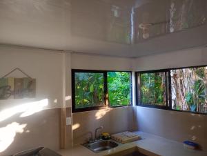 a kitchen with three windows and a sink at casa playa negra in Puerto Limón