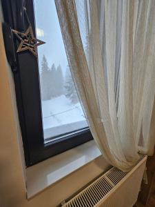 ein Fenster mit einem Vorhang und einem Stern darauf in der Unterkunft Grand Casa Apartments in Jahorina