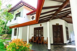 a house with a porch and chairs in it at Sandaru Villa in Weligama