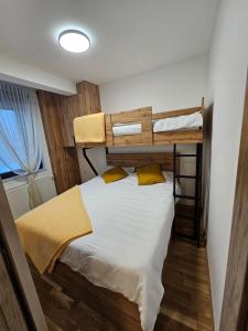 ein Schlafzimmer mit einem Etagenbett mit weißer Bettwäsche und gelben Kissen in der Unterkunft Grand Casa Apartments in Jahorina