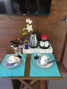 a table with two plates and a tea pot on it at Suíte Solar in Ilha do Mel