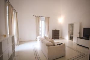 ein weißes Wohnzimmer mit einem weißen Sofa und einem TV in der Unterkunft Giù nei Sassi in Matera