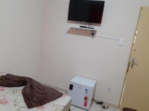a room with a bed and a television on a wall at Espaço matteo in Aparecida